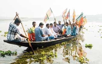 নৌকায় বাওড় পেরিয়ে তেরো ঘরের পথে বিজেপি প্রার্থী কেডি বিশ্বাস। ছবি: নির্মাল্য প্রামাণিক।