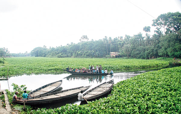 পানা সরিয়ে পারাপার। ছবি: নির্মাল্য প্রামাণিক।