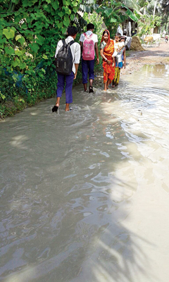 পিঠে বই, পায়ে কাদা...। নিজস্ব চিত্র।