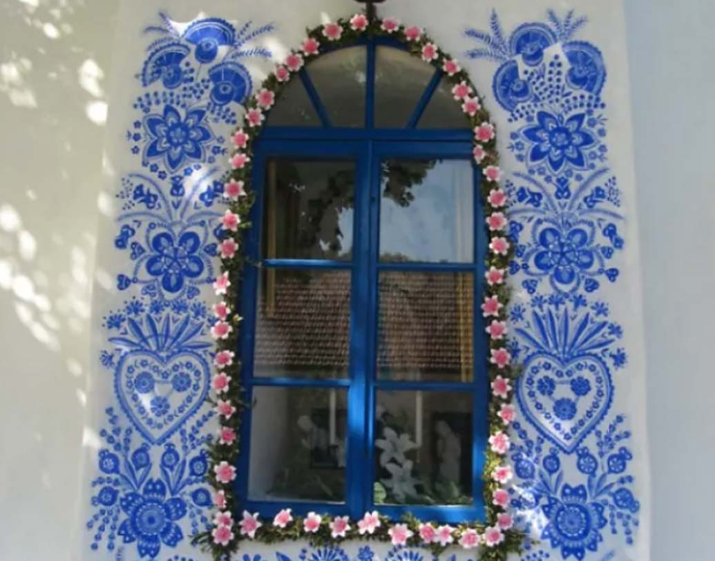 দিনরাত পরিশ্রম করেই গ্রামের বিভিন্ন বাড়ির দেওয়াল থেকে জানলা-দরজা সব জায়গাতেই ফুলের নকশা তৈরি করছেন অ্যানেজকা।