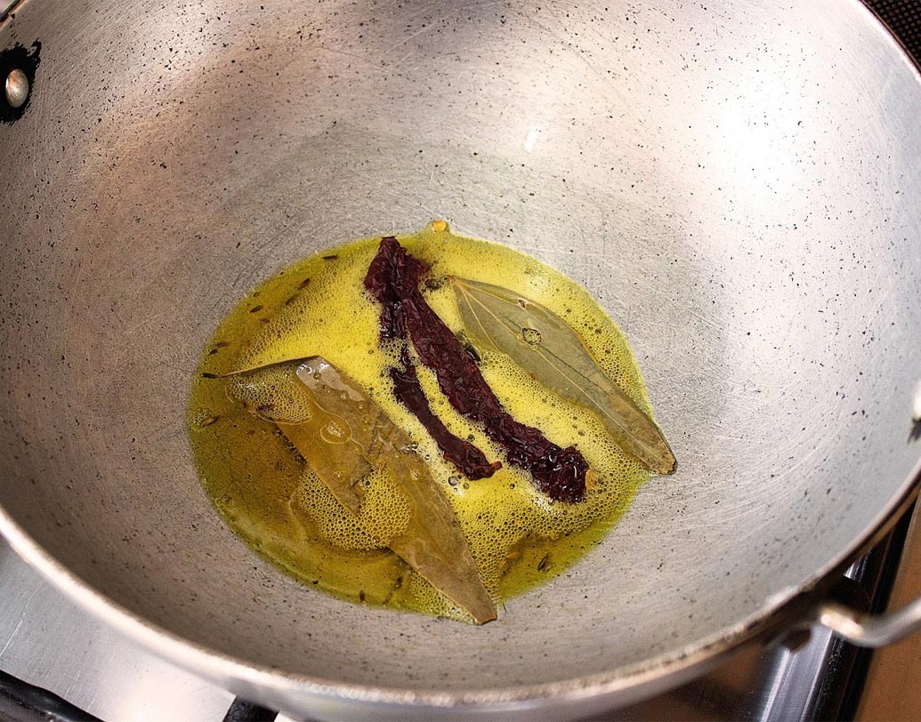 কড়াইতে তেল গরম করে তেজপাতা, গোটা জিরে, শুকনো লঙ্কা ফোড়ন দিন।