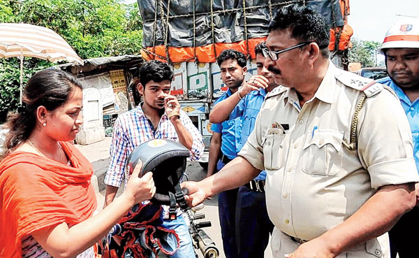 আবরণ: হেলমেট ধরিয়ে দিচ্ছেন পুলিশ। ছবি: নির্মাল্য প্রামাণিক