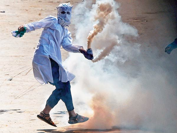 মারমুখী: শুক্রবার শ্রীনগরে সংঘর্ষ চলাকালীন কাঁদানে গ্যাসের শেল ছুড়ছে এক বিক্ষোভকারী। ছবি: পিটিআই।
