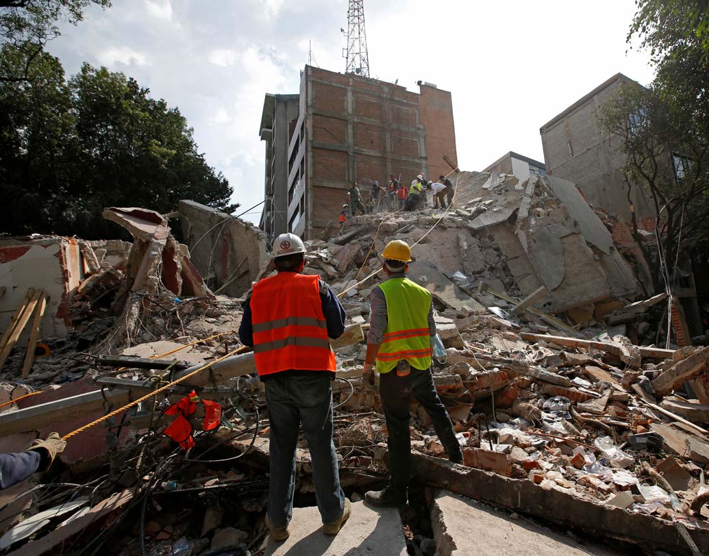 ভেঙে পড়া বহুতলের নীচ থেকে জীবনের খোঁজে মরিয়া চেষ্টায় উদ্ধারকারী দল। ছবি: রয়টার্স।