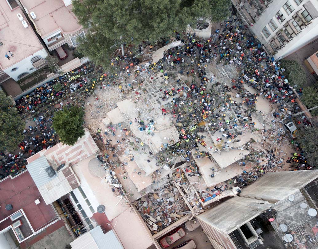 ধুলোয় মিশে গিয়েছে বহুতল। ধ্বংসস্তূপ সরিয়ে চলছে উদ্ধারকাজ। ছবি: এপি।