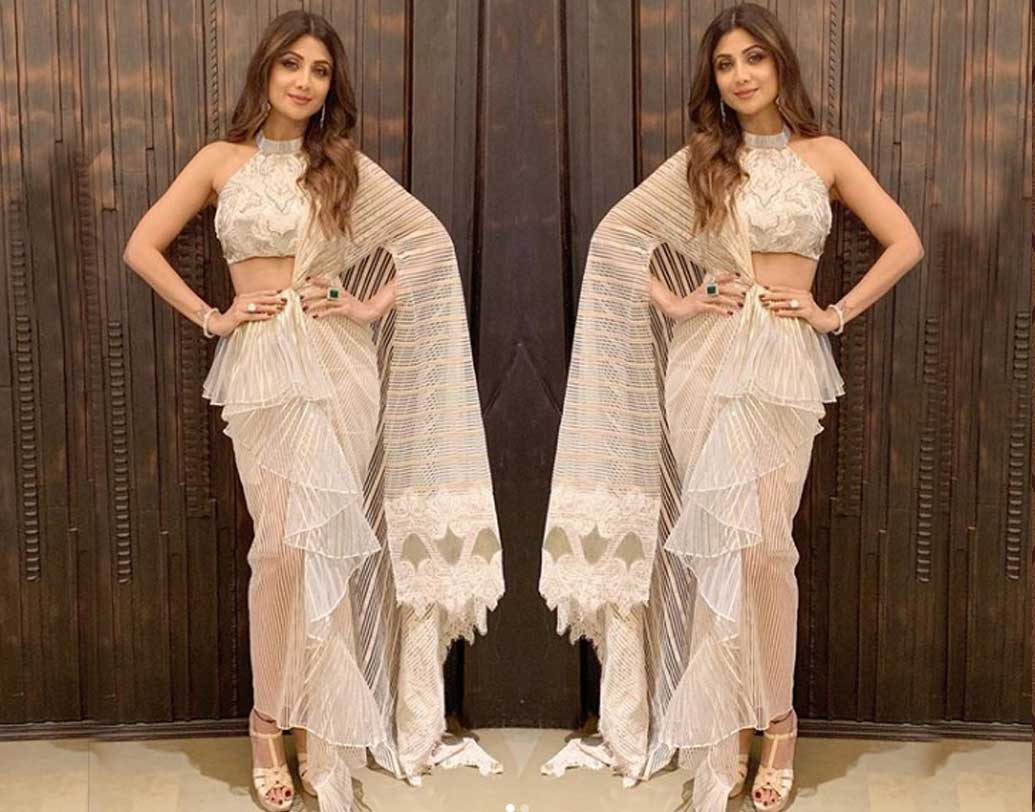 দেওয়ালির পার্টিতে একেবারে ট্রাডিশনাল সাজে ধরা দিলেন শিল্পা শেট্টি। ডিজাইনার অমিতা অগ্রবালের বানানো আইভরি শাড়ি আর ম্যাচিং দুলেই ধরে রাখলেন আকর্ষণ। তাঁর হল্টারনেক ব্লাউজের নকশা ও রং সহজেই চোখ টানে। নিজের স্টাইল ও ফ্যাশনের মেনবন্ধনে শিল্পার সাজ অনন্য হয়ে রইল পার্টিতে।