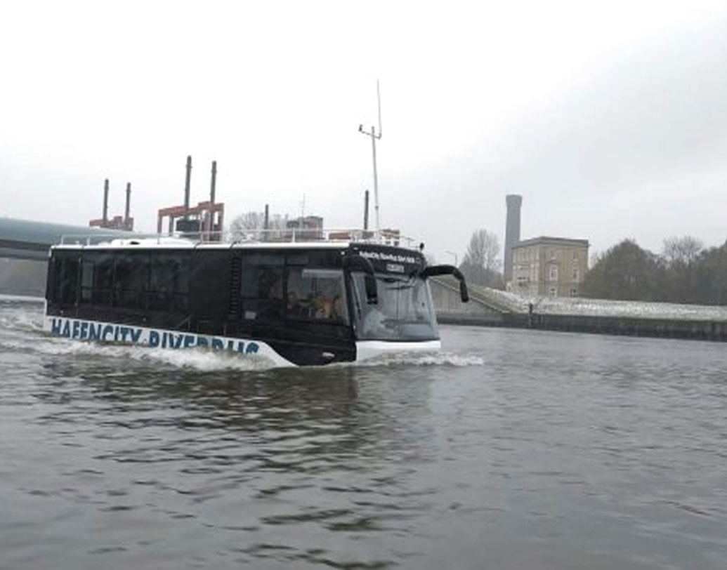 বাসে রয়েছেন যাত্রী। কোনও দুর্ঘটনা ঘটেছে এমনটাও নয় কিন্তু। একে বলা হচ্ছে ‘অ্যাম্ফিবিয়াস বাস’। কিন্তু ডাঙা ও জলে সমান স্বচ্ছন্দ এই বাস চলে কোথায়?