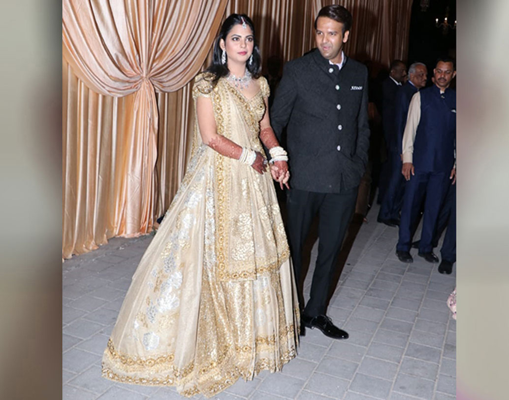 রিসেপশনের দিন সোনালি ও আইভরি রঙের ডিজাইনার লেহঙ্গায় সেজেছিলেন ইশা। সোনালি-রুপোলি ফ্লোরাল মোটিফ আঁকা এই লেহঙ্গা ভারতীয় কোনও ডিজাইনারের বানানো নয়। সুদূর ইতালির ফ্যাশন হাউজ ‘ভ্যালেন্তিনো’ তাঁর জন্য এই বিশেষ পোশাক বানিয়েছেন। আনন্দের পরনে ছিল কালো জমকালো স্যুট। দু’জনকেই খুব সুন্দর দেখাচ্ছিল এই দিন।