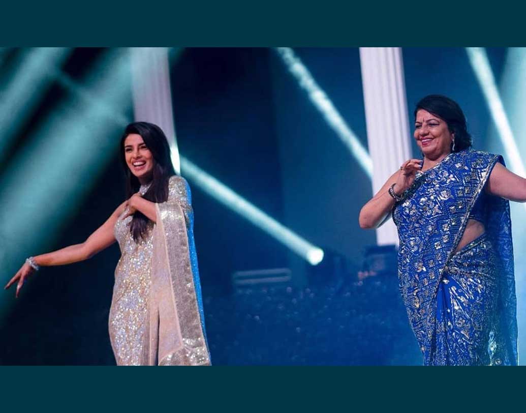 প্রিয়ঙ্কা ‘দেশি গার্ল’-এর তালে পা মিলিয়েছেন মা মধু চোপড়ার সঙ্গে। নিজে তো এমব্লেসড শাড়ি পরেছিলেন পিসি। তাঁর মাকেও দেখা গিয়েছে নীল ডিজাইনার শাড়িতে।