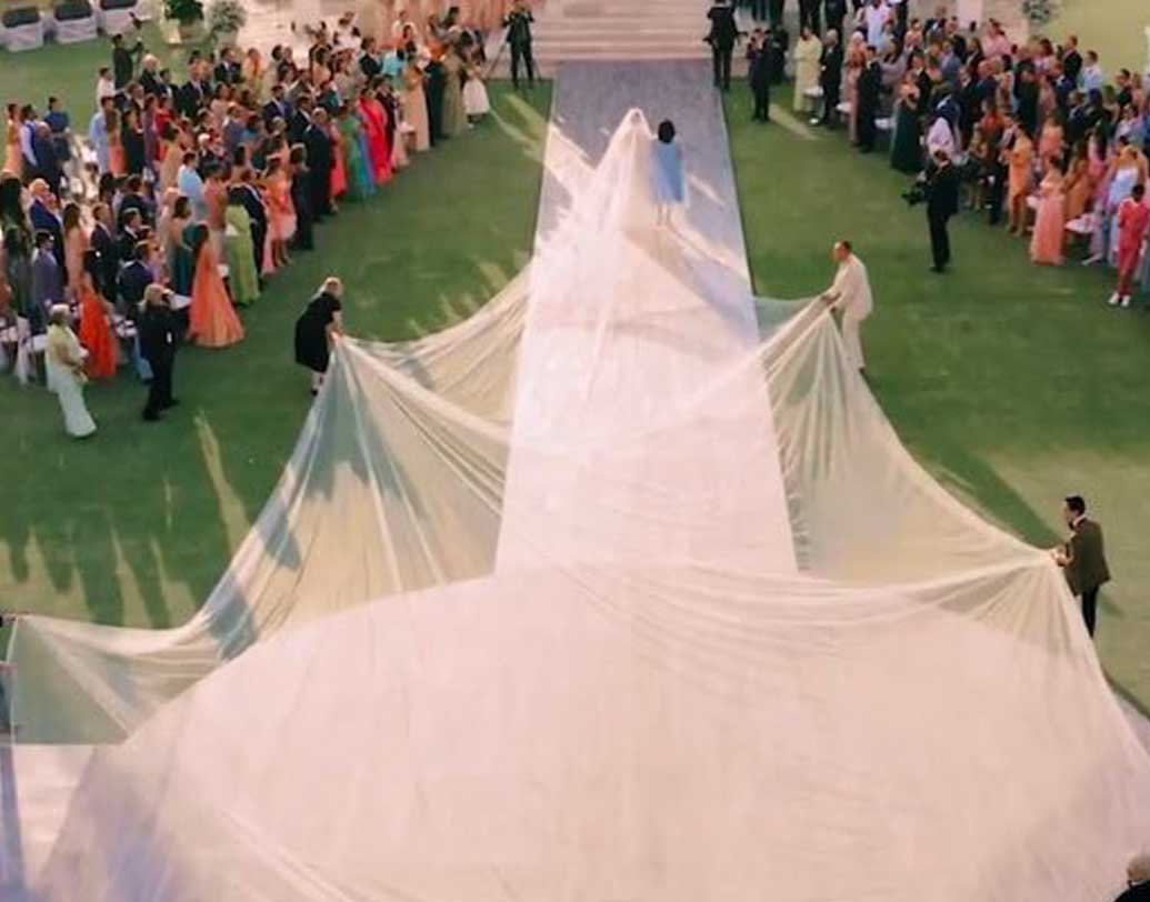 সাদা রঙের লেস বসানো, ফুলহাতা গাউন পরেছিলেন প্রিয়ঙ্কা। তাঁর পিছনে শিফনের সাদা ভেইল বসানো ছিল। কিন্তু সেটা এতটাই লম্বা ছিল যে সামলাতে হাত লাগাতে হয় জনা কয়েক লোকজনকে। ছবি: টুইটার থেকে সংগৃহীত।