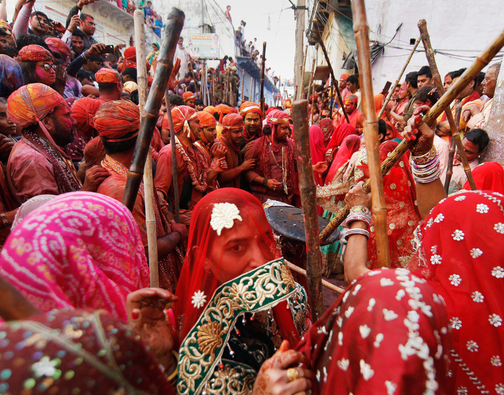 লাঠমার হোলির টানে উত্তরপ্রদেশে ভিড় জমান বহু উৎসাহী। শুধুমাত্র আবির বা রঙে মাখামাখি হয়ে হোলি খেলা নয়, বরং লাঠির ঘায়ে হোলি খেলা। কথিত আছে, গোপীনীদের উত্যক্ত করতে যেতেন কৃষ্ণের নন্দগাঁও থেকে বরসানায় যেতেন পুরুষেরা। তাঁদের লাঠিপেটা করে তাড়াতেন গোপীনীরা। মথুরা, বরসানা, নন্দগাঁওয়ের মতো জায়গায় এখনও সে ভাবেই হোলি উদ্‌যাপিত হয়। মহিলাদের লাঠির আঘাত থেকে বাঁচতে ঢালের আড়ালে চলে যান পুরুষেরা। ছবি: পিটিআই।