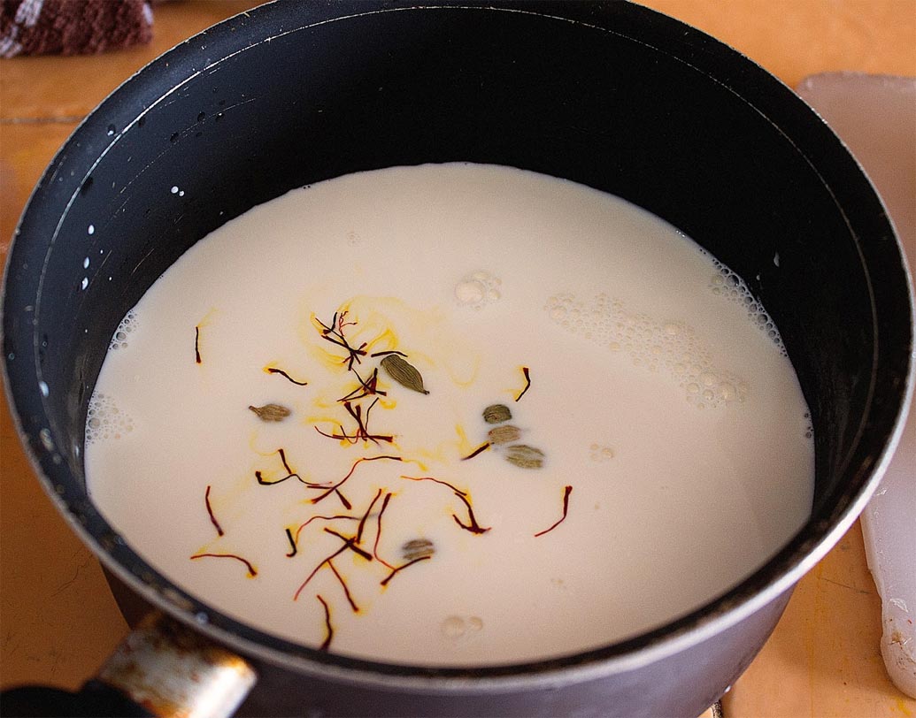 একটা সসপ্যানে একদম ঢিমে আঁচে ১ লিটার দুধ জ্বাল দিতে থাকুন। এর মধ্যে ছোট এলাচ গুঁড়ো ও কেশর দিয়ে প্রতি ২ মিনিট অন্তর নাড়তে থাকুন যাতে পাত্রের তলায় লেগে না যায়। ১৫-২০ মিনিটের মধ্যে দুধ ঘন হয়ে অর্ধেক হয়ে যাবে।