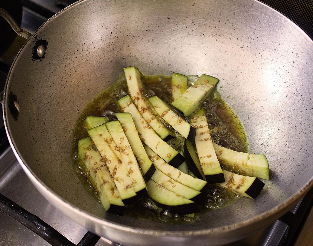 কড়াইতে তেল গরম করে বেগুন দিয়ে ভাজতে থাকুন। নরম হয়ে এলে তেল থেকে তুলে রাখুন।