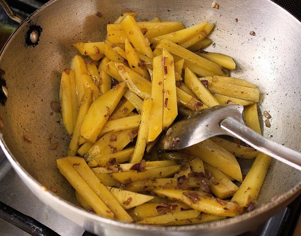 এ বার কড়াইতে লম্বা করে কেটে রাখা আলু দিন। গুঁড়ো হলুদ, লাল লঙ্কা গুঁড়ো, নুন দিয়ে ভাল করে মিশিয়ে নাড়তে থাকুন যতক্ষণ না আলু হালকা বাদামি রং ধরছে। প্রয়োজন মনে হলে সামান্য জল দিতে পারেন। চাপা দিয়ে ২-৩ মিনিট সিদ্ধ হতে দিন।