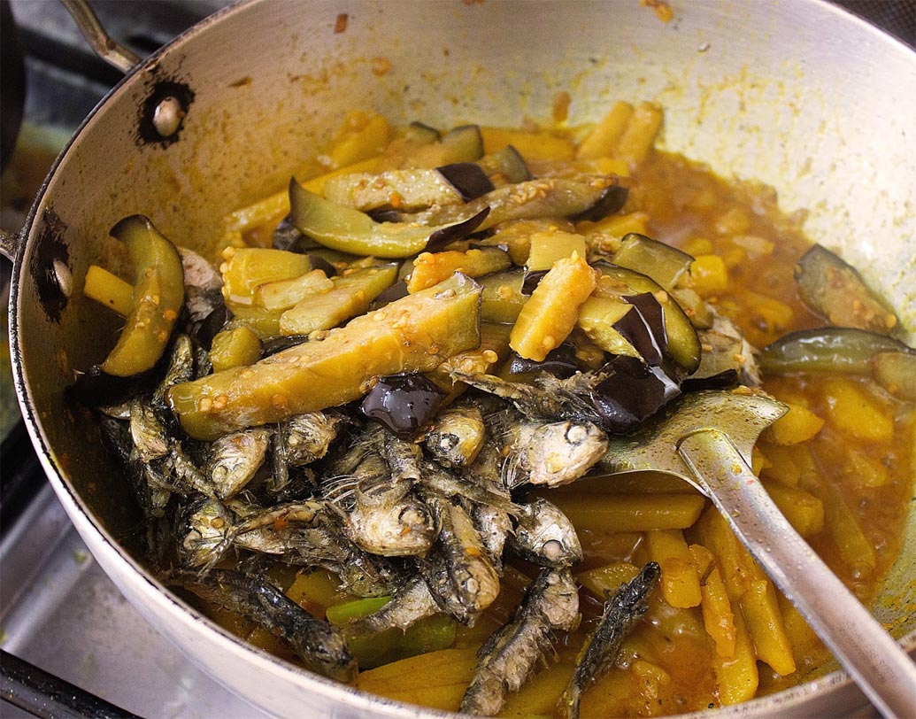 আলু ও মুলো সিদ্ধ হয়ে গেলে ভাজা মাছ, বেগুন ও চেরা কাঁচা লঙ্কা দিয়ে জল পুরোপুরি শুকিয়ে যাওয়া পর্যন্ত নাড়তে থাকুন।