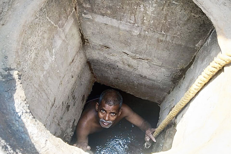 অসহায়: কলেজ স্ট্রিটে ম্যানহোল সাফাই করছেন এক কর্মী। নিজস্ব চিত্র