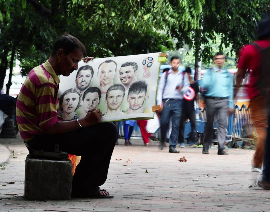 রাজভবনের সামনে শিল্পীর তুলিতে জীবন্ত বিশ্বকাপের নায়করা। আন্দ্রে ইনিয়েস্তা, লুই সুয়ারেজ, ক্রিশ্চিয়ানো রোনাল্ডো, নেমার, মেসিরা সবাই উঠে এসেছেন ক্যানভাসে। ইনিয়েস্তার তো বটেই, মেসি, রোনাল্ডো, সুয়ারেজেরও সম্ভবত এটাই শেষ বিশ্বকাপ। এর মধ্যে একমাত্র ইনিয়েস্তারই বিশ্বজয়ের অভিজ্ঞতা রয়েছে। নেমারের বয়স কম, ফের সুযোগ পাবেন তিনি।