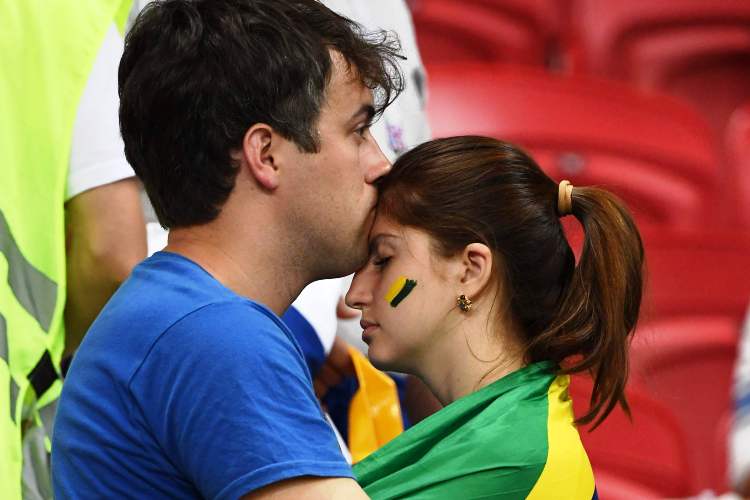 কার্ড সমস্যায় খেলতে পারেননি কাজিমিরো। আক্রমণ ও রক্ষণের মধ্যে ভারসাম্য রক্ষা করেন তিনি। তিনি খেলতে না পারায় মাঝমাঠে বিশাল শূন্যতা সৃষ্টি হয়। কাজিমিরোর পরিবর্তে আসা ফার্নান্দিনহো সেই অভাব ঢাকতে পারেননি। তাঁর আত্মঘাতী গোল হয়ে ওঠে প্রথম ধাক্কা। দ্বিতীয় গোলের ক্ষেত্রেও দায় অস্বীকার করতে পারেন না তিনি। ম্যাচের পরে ব্রাজিলের পতাকা নিয়ে শোকস্তব্ধ দম্পতির ছবি হয়ে উঠল প্রতীকী। ছবি: এএফপি।