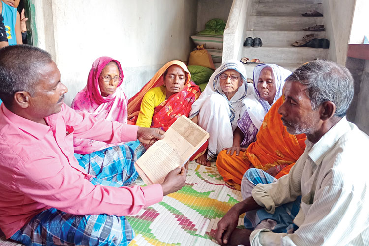 দাদা-দিদিদের সঙ্গে বসে বাড়ির দলিল দেখছেন শুক্তার আলি। সোমবার ঘুসকিরা গ্রামে। ছবি: তন্ময় দত্ত