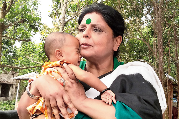 রাড়িয়ায় খুদেকে কোলে তুলে নিলেন দীপা দাশমুন্সি। ছবি: সন্দীপ পাল