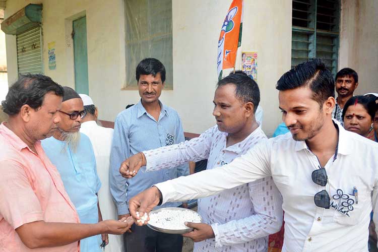 নকুলদানা বিলি করছেন তৃণমূল কর্মীরা। —নিজস্ব চিত্র।