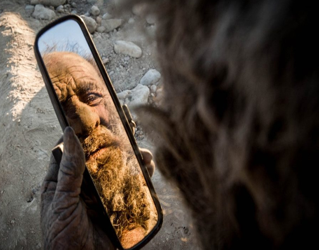 তবে এ কথা ভাবার কারণ নেই যে, আমৌ হাজি নিজের যত্ন করেন না । মাঝে মাঝেই গাড়ির ভাঙা আয়নায় দেখে নেন চেহারা।  ফুটিফাটা পোশাক পরনে নিজের মলিন চেহারাটা দেখতে তাঁর বেশ ভাল লাগে।   (ছবি: সোশ্যাল মিডিয়া)