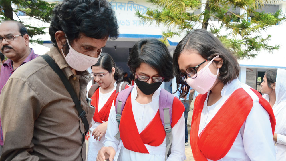 সতর্ক: করোনাভাইরাস নিয়ে আতঙ্কের মধ্যেই শুরু হল উচ্চ মাধ্যমিক পরীক্ষা। মাস্ক পরে পরীক্ষাকেন্দ্রে হাজির পড়ুয়ারা। বৃহস্পতিবার কাটোয়ায়। ছবি: অসিত বন্দ্যোপাধ্যায়