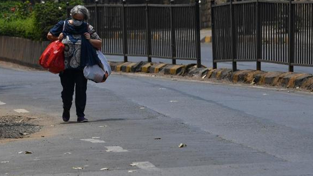 জরুরি অবস্থায় মাস্ক পরে পথে নামতে হয়েছে এই বৃদ্ধাকেও। সংগ্রহ করেছেন দীর্ঘ ঘরবন্দি-জীবনের রসদ।