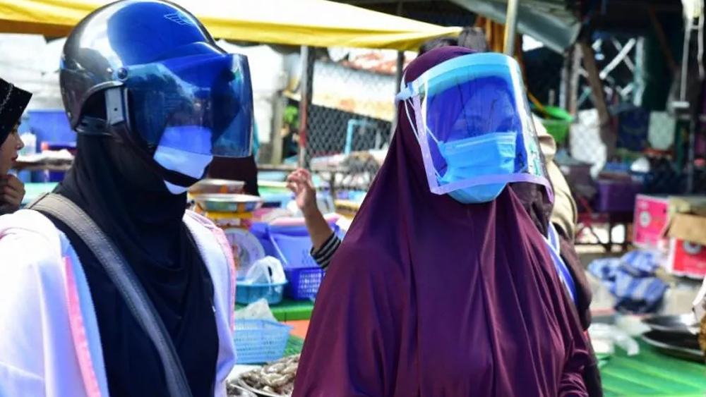 তাইল্যান্ডের মাছের বাজারে এই দুই তরুণীও মুখ ঢেকেছেন দু’ভাবে। প্রথমত মাস্কে। তাতেও নিশ্চিত না হয়ে গোটা মুখকেই ঢেকে আছে স্বচ্ছ বর্ম।