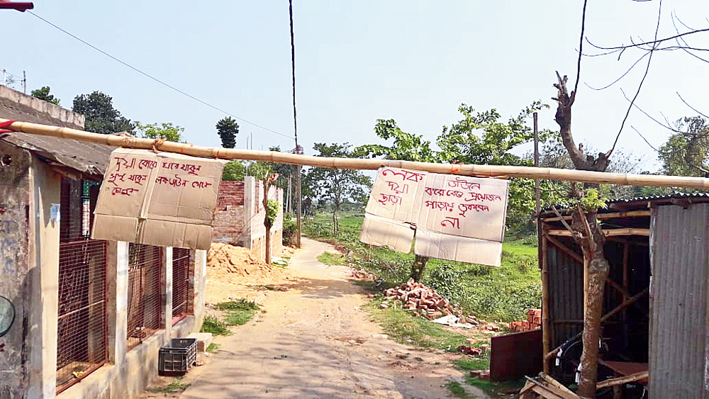 কাটোয়ার পাড়ায় পাড়ায় এ ভাবেই বাঁশ বেঁধে, প্ল্যাকার্ড ঝুলিয়েছেন এলাকার বাসিন্দারা। নিজস্ব চিত্র 