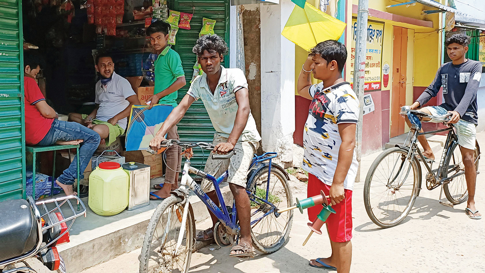 ছুটির মেজাজ: বিষ্ণুপুর শহরের বিশ্বাসপাড়ায় মুখ না ঢেকে দোকানের সমানে জটলা। চলছে গল্পগাছাও। রবিবার। ছবি: শুভ্র মিত্র