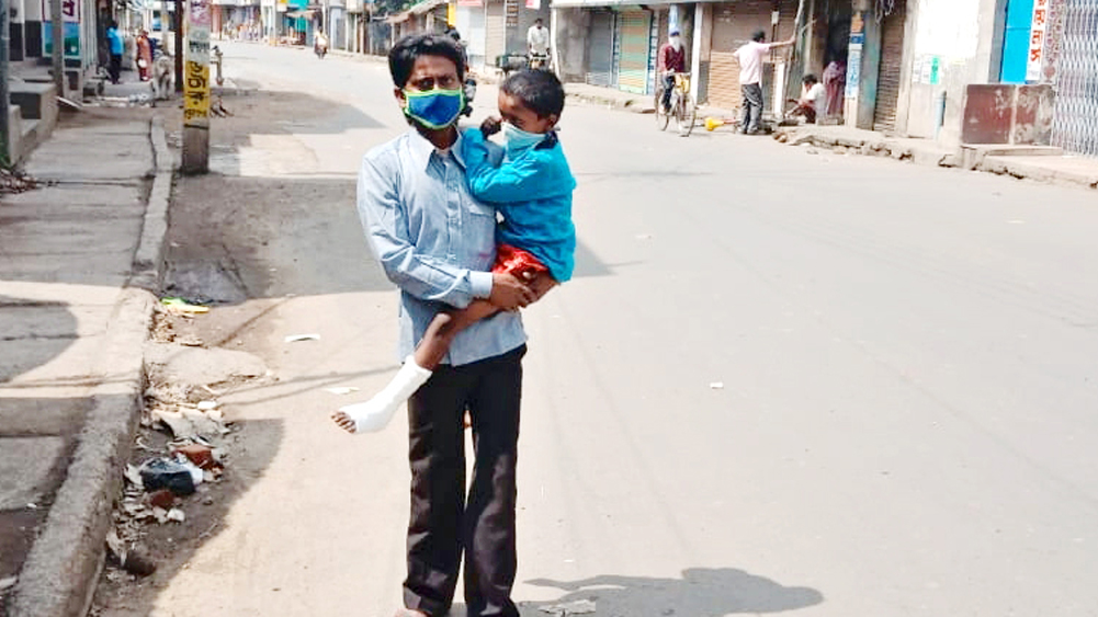 একাকী: ফাঁকা রাস্তায় ছেলেেক কোলে নিয়ে আশিস। নিজস্ব চিত্র