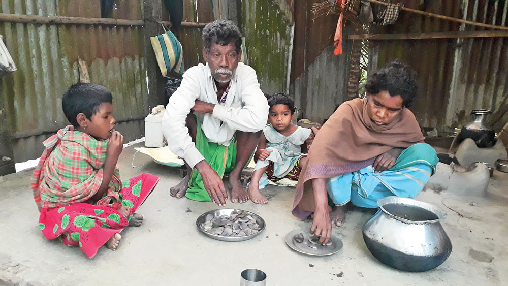 ক্ষুধা-নিবারণ: পাতে শুধু বুনো আলু সেদ্ধ। এটাই আদিবাসী পরিবারটির দুপুরের খাবার। আলিপুরদুয়ারের টটপাড়ায়।  ছবি: রাজু সাহা