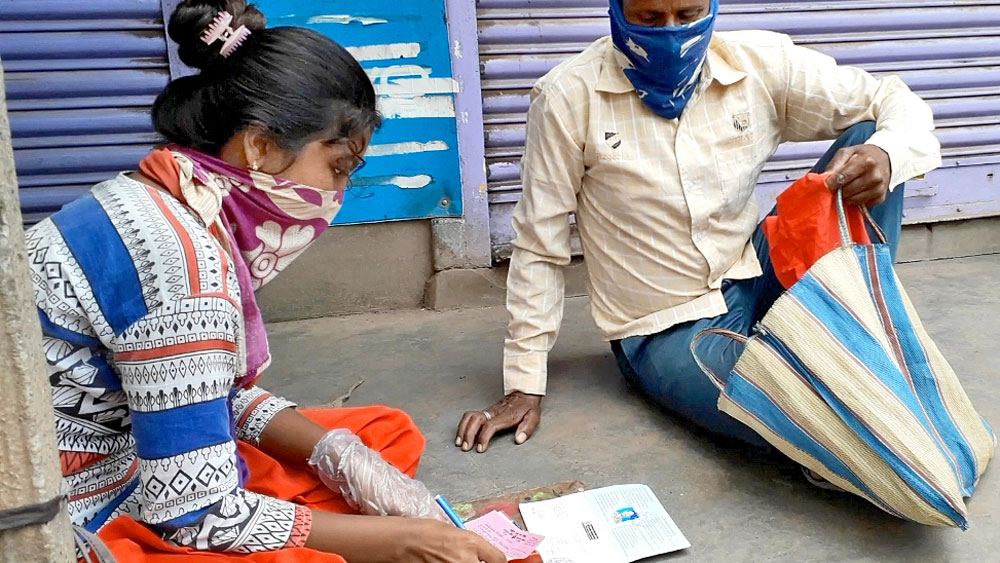 বলগোনায় ব্যাঙ্কের সামনে ফর্ম পূরণে ব্যস্ত শম্পা রুদ্র। ছবি: সুদিন মণ্ডল