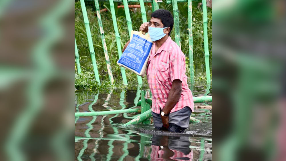 নাছোড়: হাঁটু জলে আটকে পড়ে মোবাইলে যোগাযোগের চেষ্টা। বৃহস্পতিবার লেকটাউনে। ছবি: স্নেহাশিস ভট্টাচার্য
