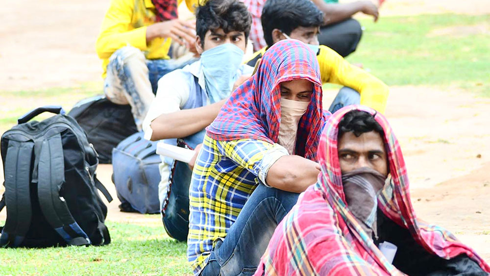 অপেক্ষা: ননীবালা স্কুলের হস্টেল মাঠে বসে রয়েছেন পরিযায়ী শ্রমিকেরা। ছবি: দেবরাজ ঘোষ