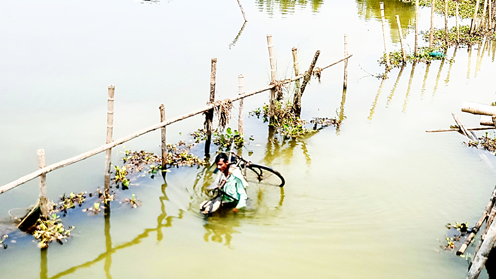 রোজ এ ভাবেই কেলেঘাই পেরিয়ে দোকান খুলতে যান শক্তি জানা। মঙ্গলবার। নিজস্ব চিত্র 