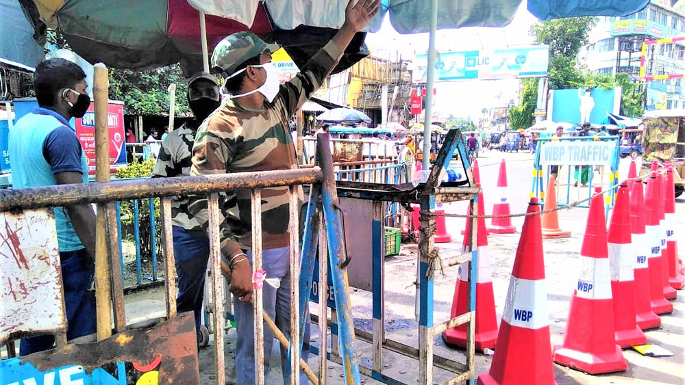 করোনা সতর্কতায় ব্যারিকেডের মধ্যে থেকে যান নিয়ন্ত্রণ ট্রাফিক পুলিশের। রথবাড়িতে। নিজস্ব চিত্র