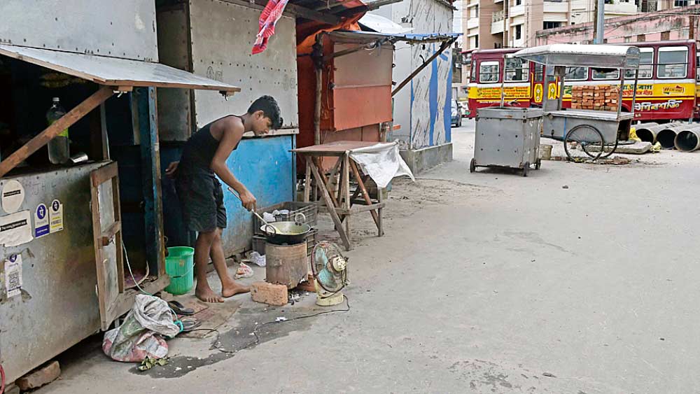 অমান্য: এলাকায় শুরু হয়েছে সাত দিনের লকডাউন। তার মধ্যেই দোকান খুলে চলছে রান্না। রবিবার, বিরাটি স্টেশন চত্বরে। ছবি: সুদীপ্ত ভৌমিক 