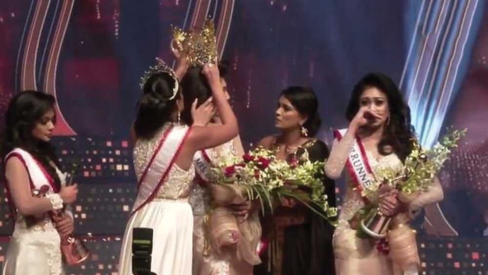 এর পরেই কার্যত চুলোচুলি শুরু করে দেন ক্যারোলিনা। মাইক রেখে পুষ্পিকার দিকে এগিয়ে যান তিনি। পুষ্পিকার মাথার মুকুট ধরে টানাটানি শুরু করে দেন। চুল ধরে টেনে হিঁচড়ে শেষমেশ মুকুটটি পুষ্পিকার মাথা থেকে খুলে নেন তিনি। তার পর সকলকে অবাক করে প্রতিযোগিতায় দ্বিতীয় স্থানাধিকারীর মাথায় মুকুট তুলে দেন।