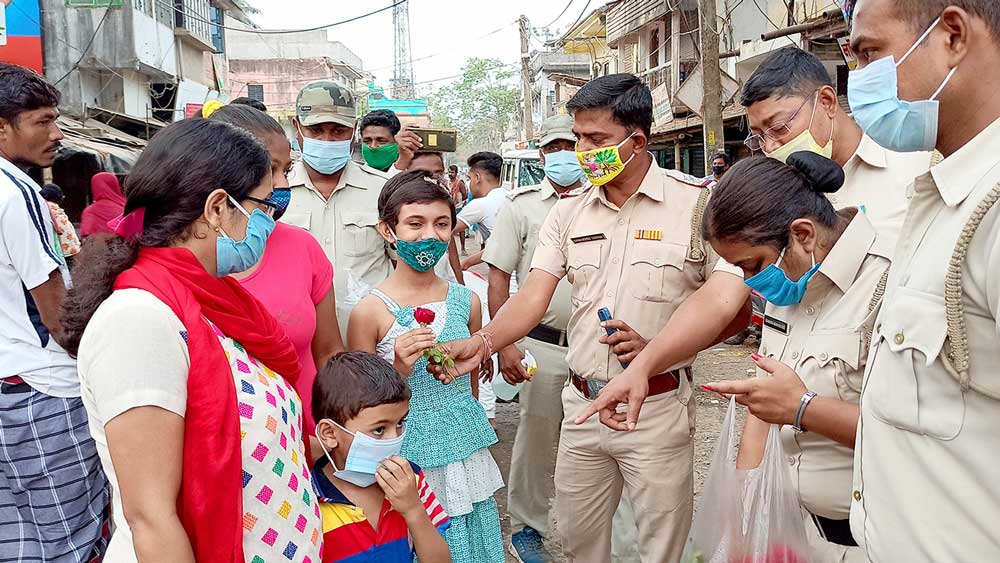  অভিনব: মাস্ক পরে থাকা নাগরিকদের হাতে গোলাপ ফুল তুলে দিচ্ছে পুলিশ। 