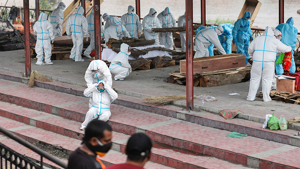 স্বাস্থ্যকর্মী এবং মৃতের পরিজনরা পিপিই পরেছেন। স্বজন হারানোর এই ছবি জম্মুর।