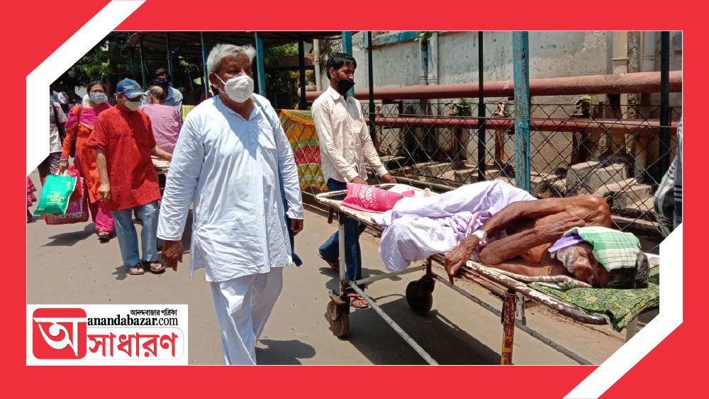 অসুস্থ বৃদ্ধকে ওয়ার্ডের দিকে নিয়ে যাচ্ছেন ‘হাসপাতাল দাদা’।