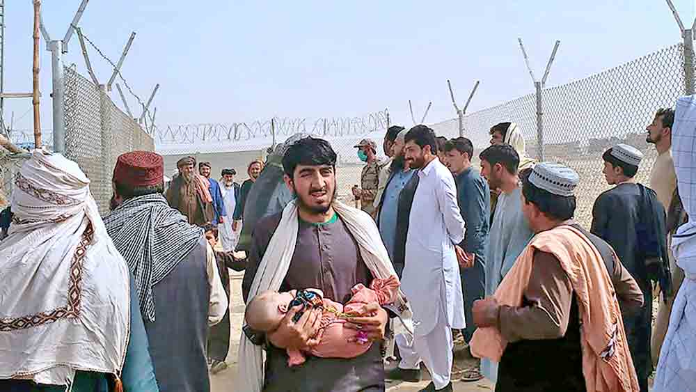 কোলে শিশু। তালিবানের হাত থেকে বাঁচতে পাক-আফগান সীমান্তে সন্ত্রস্ত আফগান নাগরিক।