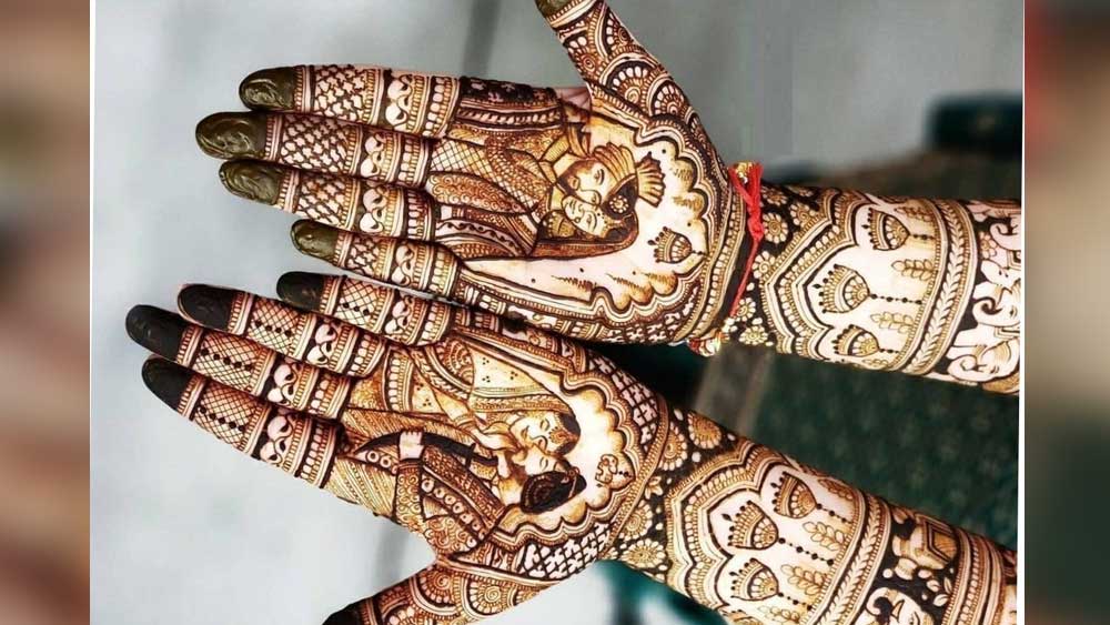 ৩. বর-বউ মেহেন্দি : আপনি যদি হাতজোড়া ঐতিহ্যবাহী মেহেন্দির নকশা পছন্দ করেন, তা হলে এই ধরনের মেহেন্দির নকশা আপনার জন্য এক্কেবারে আদর্শ পছন্দ হবে। এই মেহেন্দির বিশেষত্ব, কনের হাতে বর এবং কনের বিয়ের সাজ তুলে ধরা হয়।