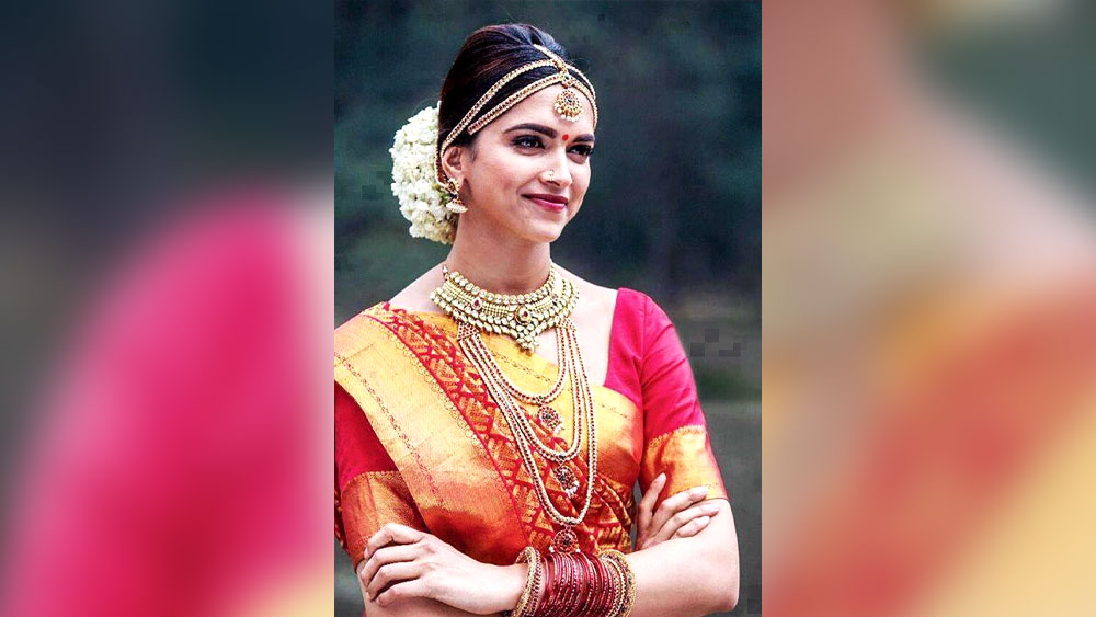 চেন্নাই এক্সপ্রেস:  বিয়েতে যদি বৈচিত্র চান, সেজে উঠুন দক্ষিনী সাজে। ঠিক যেমনটা সেজেছিলেন ‘চেন্নাই এক্সপ্রেস’-এর দীপিকা পা়ড়ুকোন। একদম সনাতনী দক্ষিণী সাজ, লাল জমির উপর সোনালি জরির কাজ এবং চওড়া সোনালি পাড়ের কাঞ্জীভরম শাড়ি। সঙ্গে সোনা, মুক্ত এবং লাল-সবুজ পাথর বসানো সাবেকি দক্ষিণী গয়না, কানে টানা দুল। মাথায় চওড়া টায়রা টিকলি, খোঁপায় জুঁইয়ের মালা। বিয়ের দিন এই সাজ আপনিও করে দেখতে পারেন।