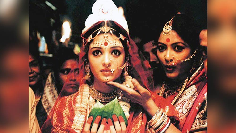 চোখের বালি: বাঙালি বধূর চিরাচরিত সাজ কার না ভাল লাগে? আর পর্দায় নায়িকাদের সবচেয়ে সুন্দর ভাবে সাজিয়েছিলেন ঋতুপর্ণ ঘোষই। ‘চোখের বালি’র বিনোদিনীর (ঐশ্বর্যা রাই বচ্চন) লাল টুকটুকে বেনারসীর কে-ই বা ভুলতে পারেন? কপালের চন্দনের নকশা যত্ন করে এঁকেছিলেন পরিচালক নিজেই। সনাতনী সাজ ভাল লাগলে নির্দ্বিধায় আপনি এই সাজ ফুটিয়ে তুলতে পারেন। 