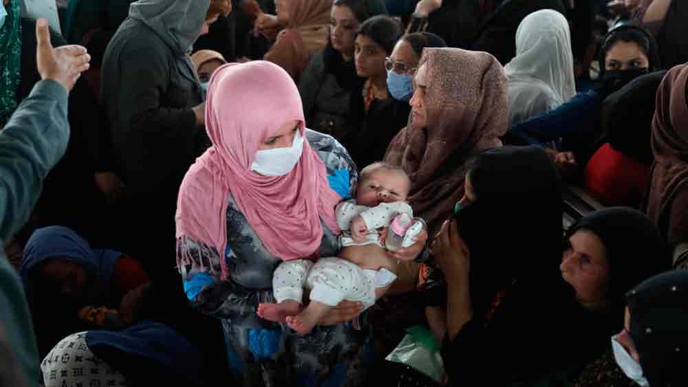 কাবুলে পাসপোর্ট দফতরের বাইরে সন্তান কোলে নিয়ে ভিড় মহিলাদের। 
