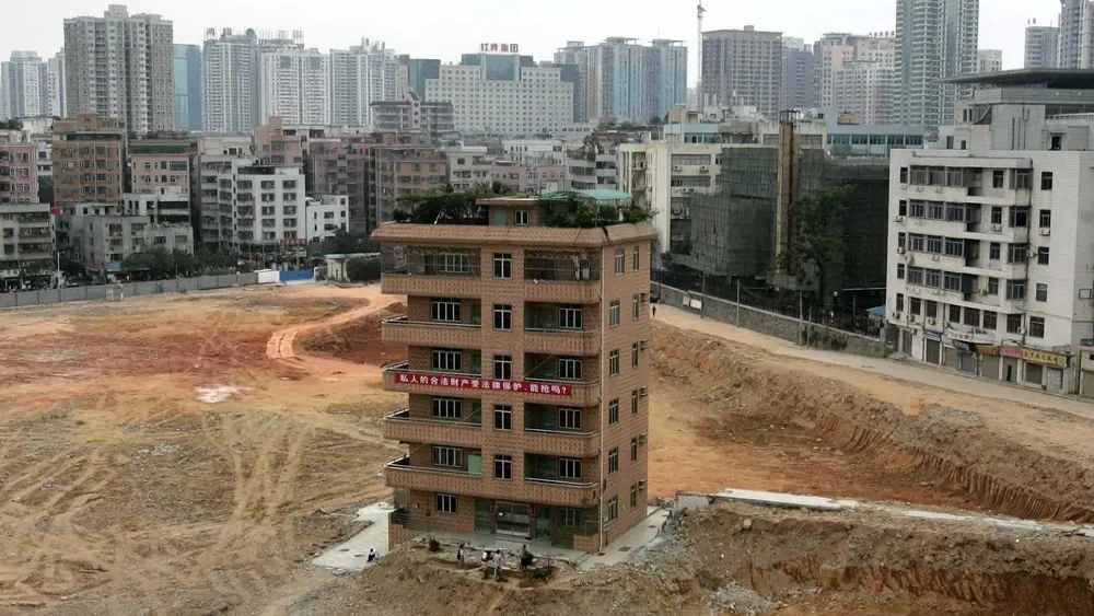 নেল হাউস বা কাঁটা বাড়ি। চিনের দেওয়া সংজ্ঞা অনুযায়ী কাঁটা বা়ড়ি সেগুলিই যা ‘উন্নয়নের পথের কাঁটা’ হয়ে দাঁড়িয়ে আছে। নেল অর্থাৎ কাঁটা পেরেক। কেন এই নামকরণ তার একটা ব্যাখ্যাও আছে। চিনের ব্যাখ্যা অনুযায়ী অনেকটা কাঠের তক্তায় বেঁধা বেয়ারা পেরেকের মতো এই সব বা়ড়ির মালিকের হাবভাব। পেরেকের মতো তাকে পুরোপুরি তুলে ফেলা যায় না। আবার হাতুড়ির এক ঘায়ে বসিয়ে দেওয়াও যায় না। কাঁটার মতোই অস্বস্তিকর তার অস্তিত্ব। তাই বাড়ির এই অদ্ভুত নামকরণ।