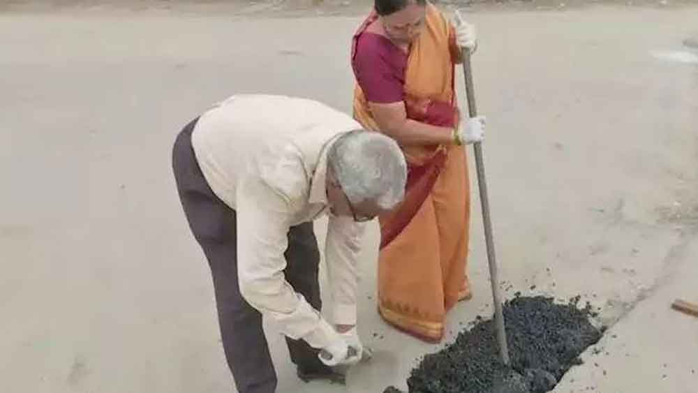 রাস্তায় গর্ত সারাই করছেন কাটনাম দম্পতি।